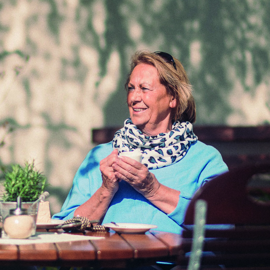 Frau benießt einen Kaffee in der Gartenwirtschaft