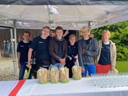 Eine Gruppe von BVB Teilnehmern und Sophie Altenburger, die BVB Leitung stehen hinter einem Tisch auf dem viele Gläser stehen. Alle lächeln in die kamera.