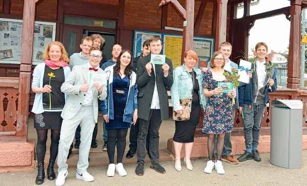 Der gesamte Kurs 17 steht mit Sophie Altenburger (Bildungsbegleitung) vor dem Bahnhof Himmelreich zum Foto für den Abschluss